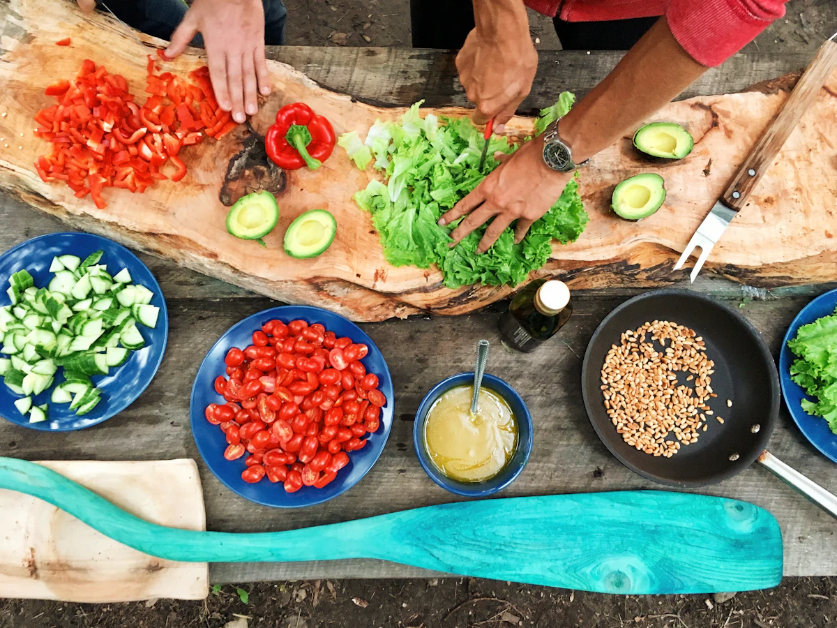Mani che tagliano verdure fresche su un tavolo di legno